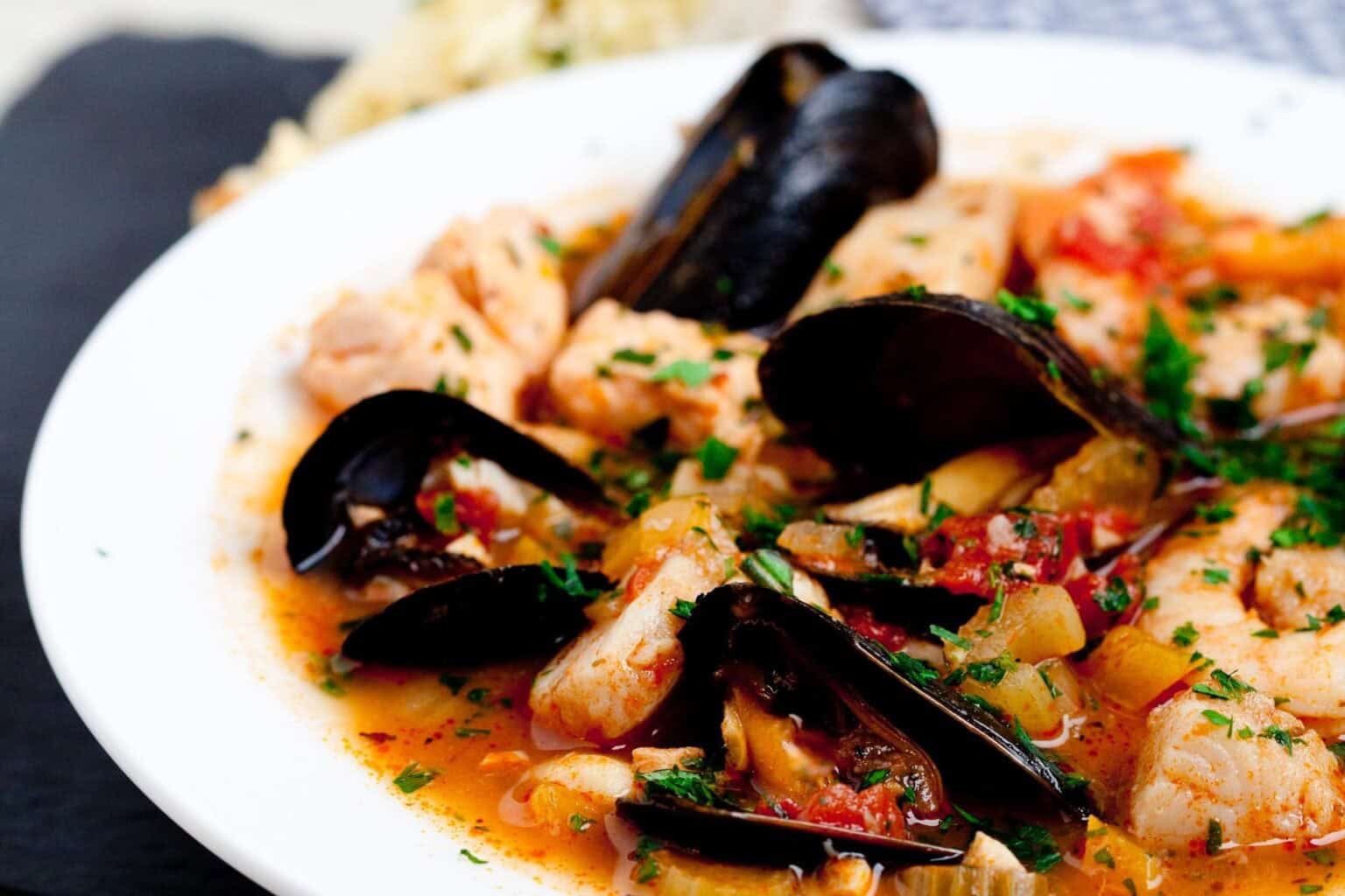 Delicious seared scallops with mussels and herbs in a flavorful sauce.
